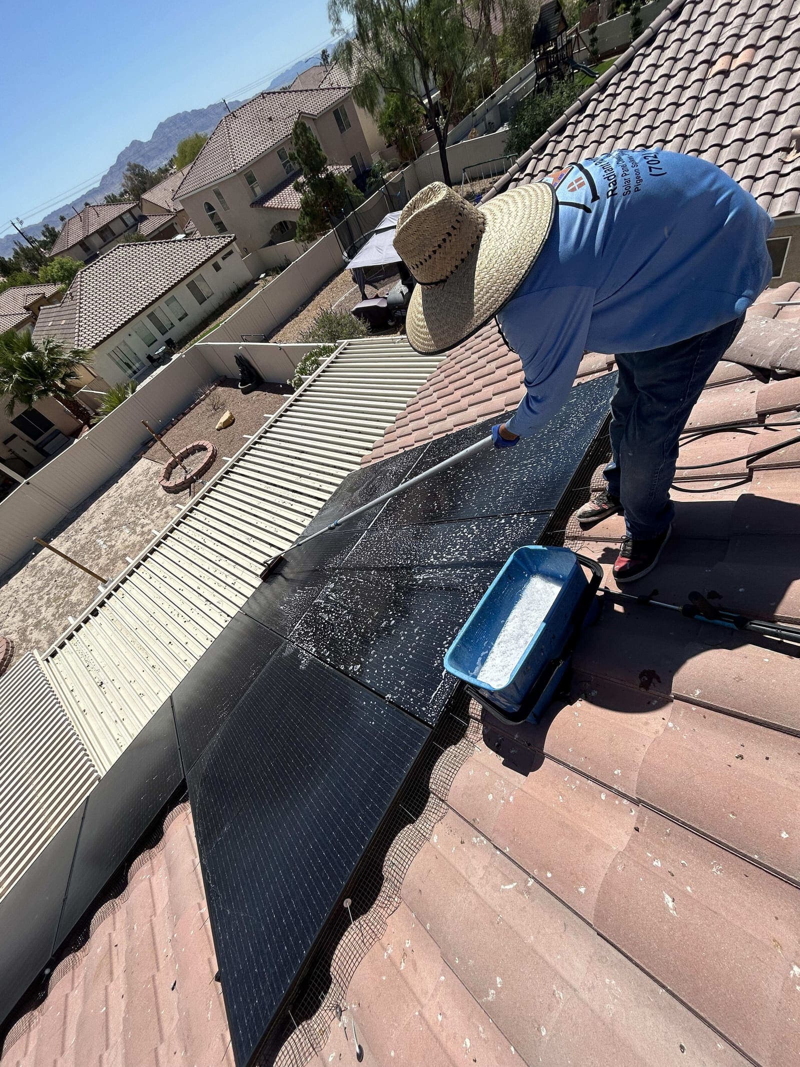 Technician cleaning solar panels with Las Vegas mountains in the background