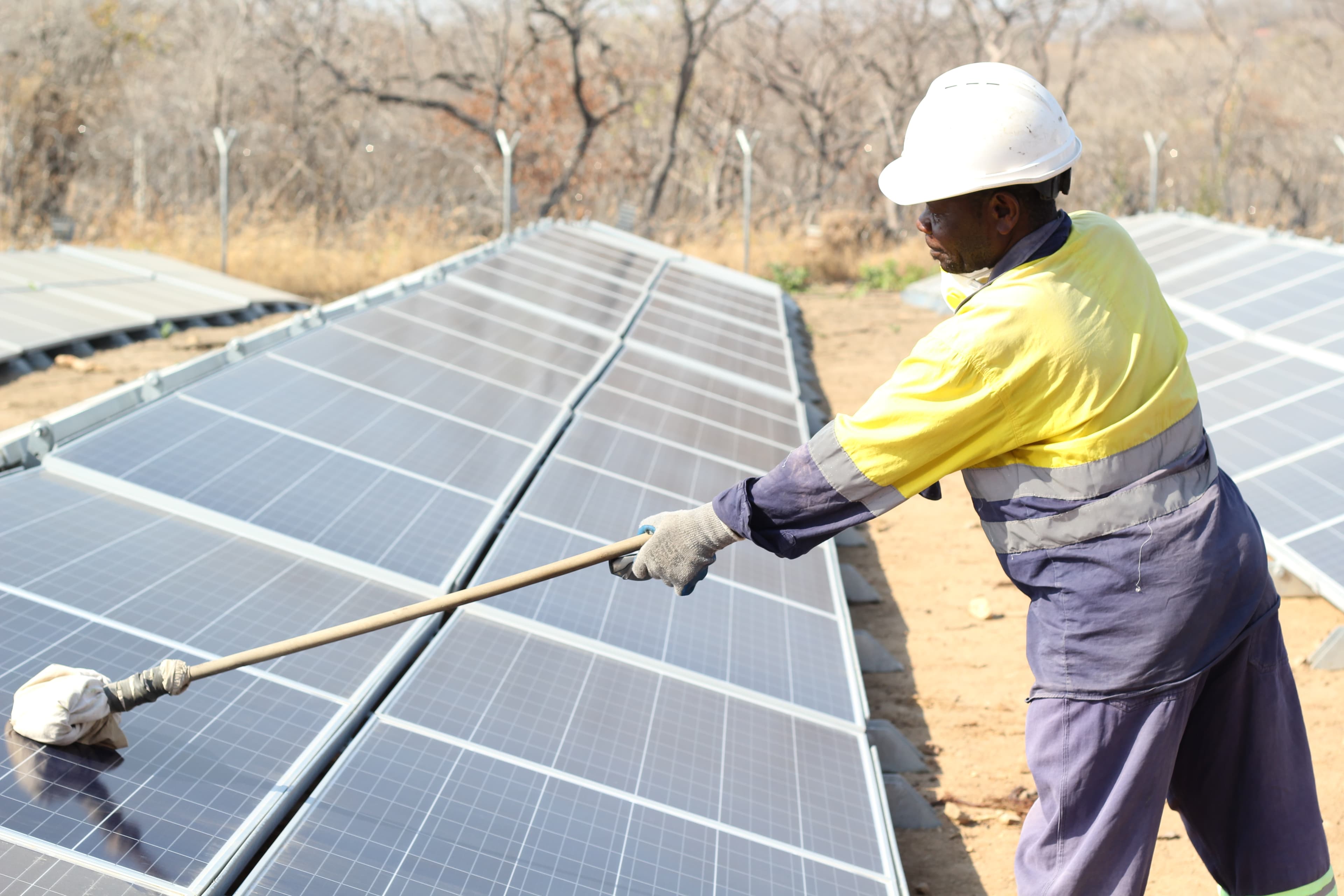 Técnico limpiando un sistema de paneles solares bajo el sol del desierto
